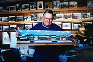 Toymaker Chris Morley holding his wooden train-trolley masterpiece.