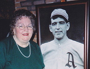 Cathy King Eddie poses beside portrait of Ira Felix Thomas